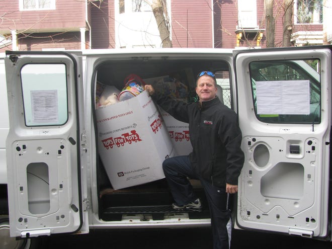 Milford Youth Center Director Jim Sanchioni stands with the overloaded van of toys donated to the drive. Imperial Cars of Mendon donated the van to make the toy delivery.