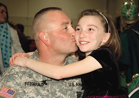 Major Mark Fitzgerald gives his daughter a kiss after surprising her at Sacred Heart's Christmas Show Thursday Night in Hampton. Photo Chris Shipley