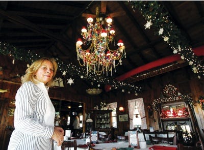 Photo by Amy Paterson/New Jersey Herald 
Kathleen Snyder, owner of the Boat House restaurant on Swartswood Lake, poses with the giant chandelier draped with hundreds of beads and Christmas ornaments that now hangs in her restaurant’s dining room.