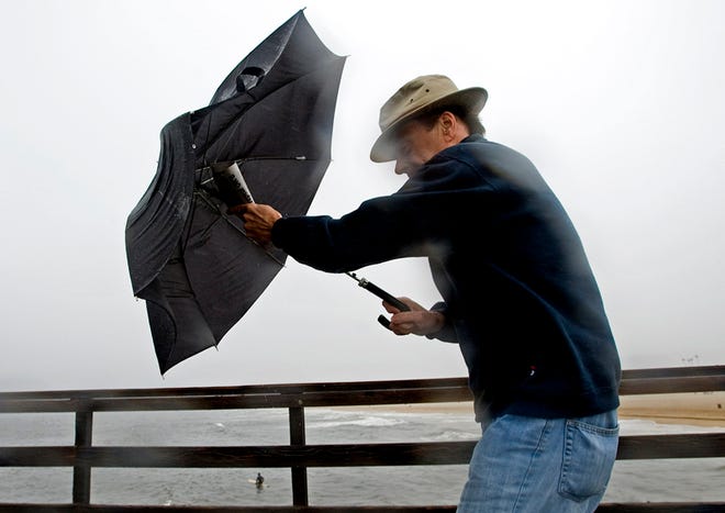 Art Ambrush uses his umbrella as a shield against the rain Sunday morning, Dec. 19, 2010, in Seal Beach, Calif. A wet pre-winter storm dumped as much as 7 inches of rain on parts of Southern California over the weekend, triggering scores of accidents, a few minor mudslides and forcing the cancellation of Sunday's final seven horse races at Hollywood Park.