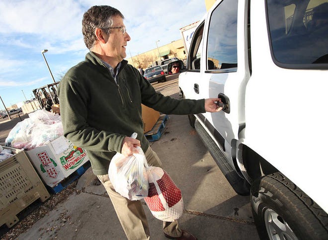 David Weaver, executive director of the South Plains Food Bank, loads frozen turkeys into a car on Tuesday at the food bank. The food bank on Tuesday continued handing out of Christmas boxes to qualified families and toys for their children.
