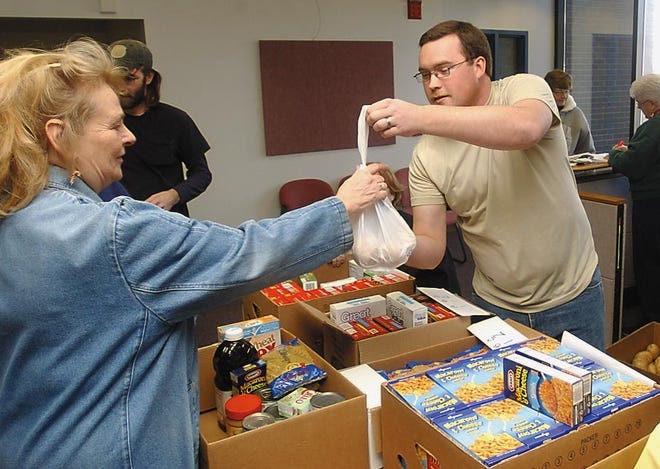 Volunteer Matthew Rodenbaugh hands Jewel Corby a bag of potatoes for her box of food at the Salvation Army food and gift give-away Tuesday in Corning.