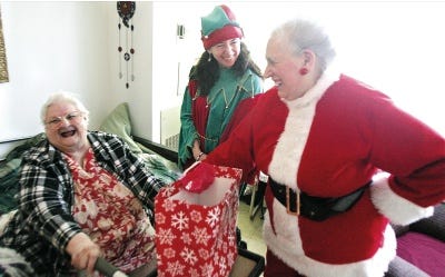 Photo by Amy Paterson/New Jersey Herald 
Gloria Bell, of Newton, left, joyfully reacts to her Christmas gifts, presented by Meals on Wheels volunteer Grace Lukawski, right, and program director Linda Ward, center.