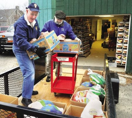 Bob White, left, and Mike Kleist, help load turkeys and hams at the York Food Pantry Monday, Dec. 20, for transport to the hall at St. Christopher Church, where volunteers stood ready to pack more than 100 holiday baskets. On Sunday, Dec. 19, volunteers stuffed empty wine boxes gathered from Hannaford with canned food and other nonperishable items. On Monday, they began adding the fresh turkeys, hams, vegetables, fruit, pies and rolls, for distribution from the church around 11 a.m. Monday. Deliveries were made to senior citizens and others who couldn’t come in to pick up the boxes.
There’s plenty of food to fill the holiday baskets, said York Food Pantry Director Pat Whalen, who is happy to have leftovers after the holidays, when donations traditionally drop. 
“We’re doing very well,” said Whalen. “People are more generous.”
Whalen is seeing an increase in the number of families coming in to the pantry this year, she said, from 40 to 42 per week in 2009 to about 50 to 56 people per week this year.
