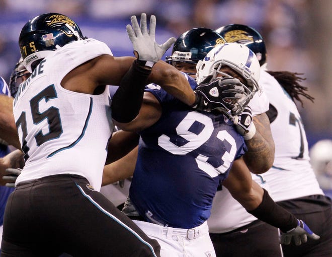 Indianapolis Colts defensive end Dwight Freeney (93) is held up by Jacksonville Jaguars offensive tackle Eugene Monroe (75) and center Brad Meester as he rushes Sunday during the fourth quarter. The Associated Press