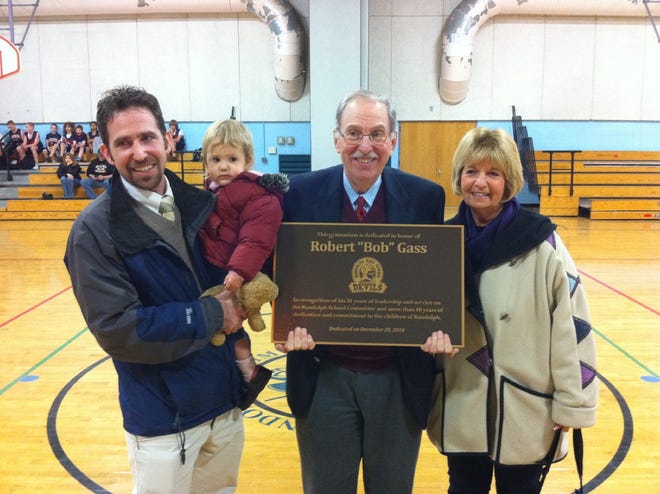 Robert Gass holds the plaque given to him at the ceremony dedicating the Randolph Community Middle School gym in his honor, Monday, Dec.20. Standing at his right is his wife, Diane, and on the left, his son Michael with Robert Gass' granddaughter Phoebe.