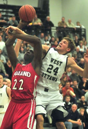 Dennis R.J. Geppert/The Holland Sentinel 
Holland's Coreontae DeBerry (22) puts up a shot while West Ottawa's Andrew Maxey (24) tries to block his shot Tuesday night at West Ottawa.
