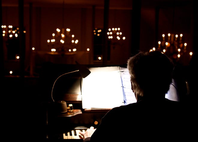 Steve Holden plays the organ from music lit by one of the few electric lights before the candle-lit Christmas service at the Colony Church in Bishop Hill on Saturday.