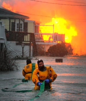 Scituate firefighters John Reidy, front, and Joe West try to get a hose to prevent a third house from burning on 7th Avenue in Scituate on Monday, Dec. 27, 2010.