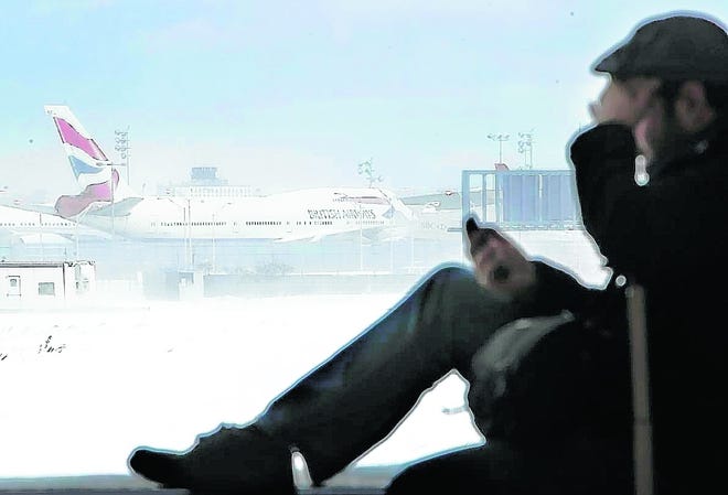 Kevin Fagan of San Francisco talks on his phone while a plane sits 
motionless on the runway Monday at John F. Kennedy International Airport in 
New York. Operations were beginning to resume at the airport Monday 
evening.