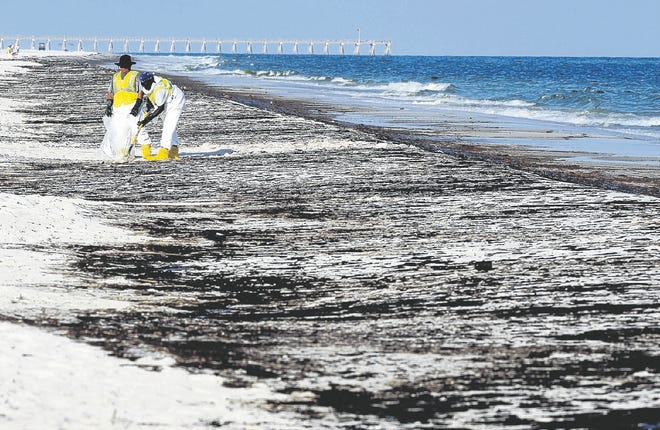 Crews work to clean up oil on Pensacola Beach from the Deepwater Horizon oil spill in this June 23 file photo.