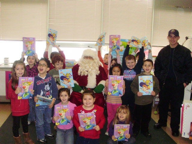 Members of Ms. Proctor’s kindergarten class at the Oaklandvale Elementary School show off their gifts. Also featured is Santa, played by Ray Lawrence, and firefighter helper Alex Watton.