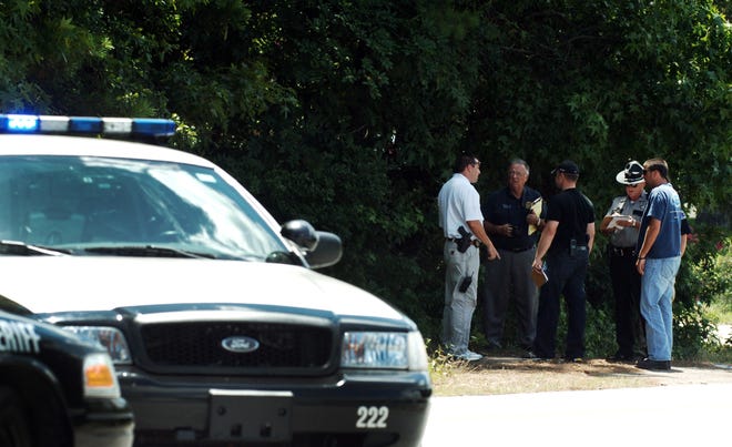 Investigators talk at the entrance to woods where two people were found dead from gun shot wounds to the head, across from Glenn Hills Middle School, Monday, July 5, 2010, in Augusta, Ga.