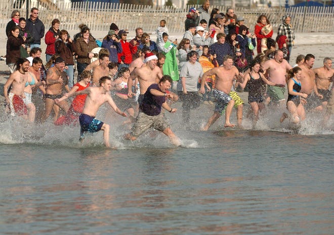 About one hundred people run into the water at Eastern Point Beach in Groton Saturday, January 1, 2011, to take part in the Samaritan Swim, an event benefiting Malta Ministries of Groton. Malta Vice President David Michaud, front center in the purple shirt, leads the crowd.