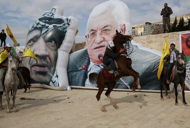 With the background of huge portraits of Palestinian President Mahmoud Abbas, right, and late Palestinian leader Yasser Arafat, Palestinian Fatah supporters gather during a rally to mark the 46th anniversary since the group's foundation in the West Bank town of Nablus, Sunday, Jan. 2, 2011. (AP Photo/Nasser Ishtayeh)