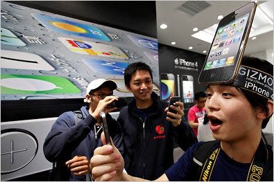 Mitsuro Endo, right, and others trying out the latest iPhone 4 at a SoftBank store in the Harajuku district in Tokyo.