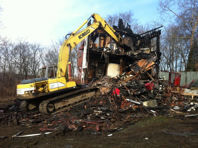 An excavator knocks down the remains of 24 John Street in Norwich after an early morning fire.
