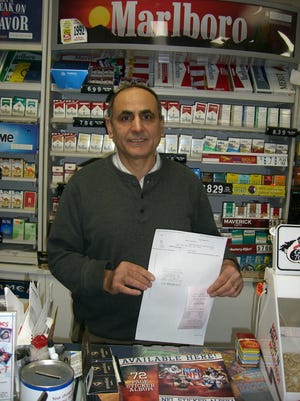 Store owner Ahmed Mousa holds the slip from the winning ticket he told Tuesday.