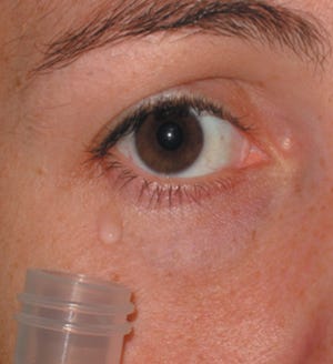 This undated handout photo provided by the journal Science shows a donor woman watching sad films in isolation, using a mirror to capture tears into a vial. If a crying woman's red nose isn't a big enough turnoff to a man, a surprising experiment found another reason: Tears of sadness may temporarily lower his testosterone level. (AP Photo/Science)