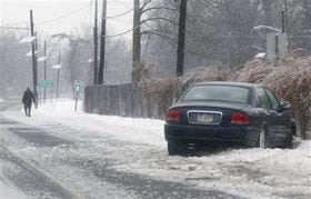 A man walks from his car after sliding off an icy road Tuesday, Jan. 18, 2011, in West Trenton, N.J. Freezing rain made roads slick throughout the region. (AP Photo/Mel Evans)