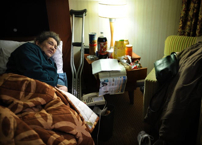 Laura, who is chronically homeless, lies in bed in her motel room.