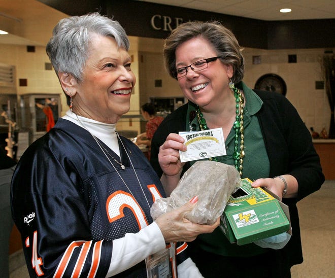 Kathleen O'Connell (right) shows Jan Hagenlocher her piece of "Frozen Tundra" Friday, Jan. 21, 2011, in the cafeteria at SwedishAmerican Hospital. Employees at the hospital can wear their favorite team apparel to celebrate this weekend's games.