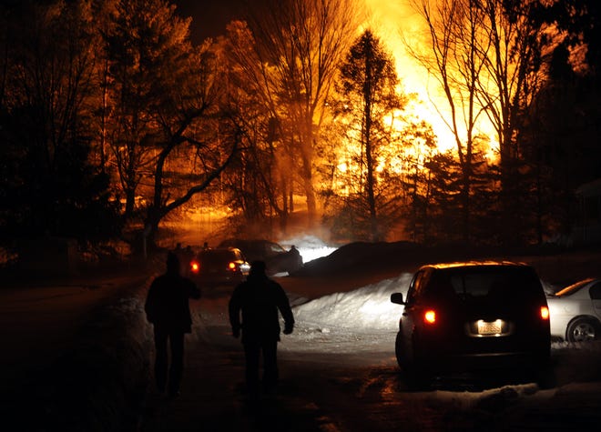Flames erupt into the night sky at the height of Saturday night's fire on Great Road. Onlookers walk towards the fire down a driveway off Crescent Street.