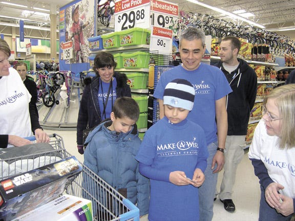 Caleb Dunahee of Fairbury looks over his selections of electronic games and toys. Next to him is his cousin, Payton Dunahee, also of Fairbury, and behind them are Caleb’s parents, Joanne Dunahee and Keith Dunahee. Standing inthe background is Alex Snieski, electronics clerk at Walmart and at right is Make-a-Wish volunteer Rita Dempsey.