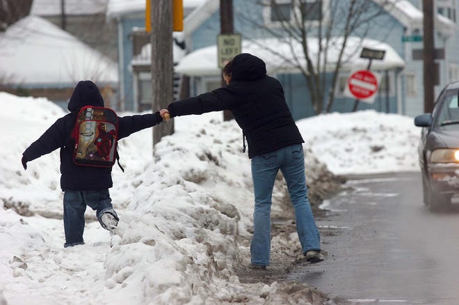 Melody Semidey of Brockton holds the hands of her son Vincent, 6, as he walks on the icy sidewalk on Crescent Street after school on Tuesday.