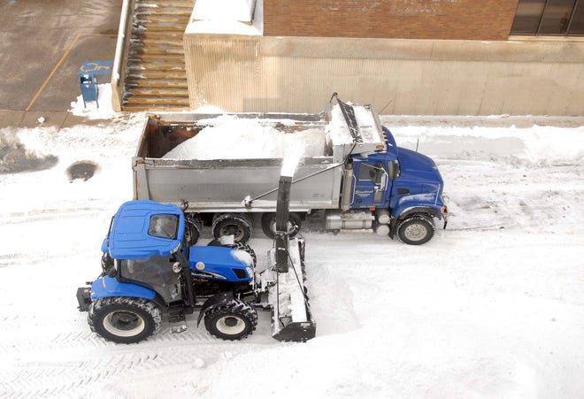 Snow is blown in to a dump truck Friday after Norwich Public Works employees used a similar vehicle to blow snow of the roof of the Water Street Garage and on to Market Street for removal in downtown Norwich.