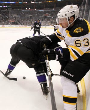 Los Angeles Kings defenseman Jack Johnson, left, checks Boston Bruins left wing Brad Marchand during the first period of an NHL hockey game in Los Angeles, Monday, Jan. 24, 2011.