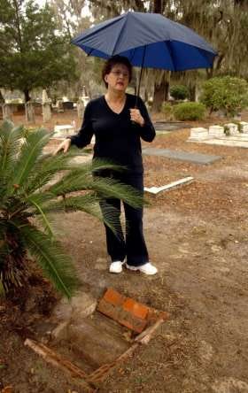 Kay Westberry stands beside a grave at Oak Grove Cemetery of a 3-year-old child who died in 1918. Westberry, a historian, is finding graves, some badly marked, and identifying them.