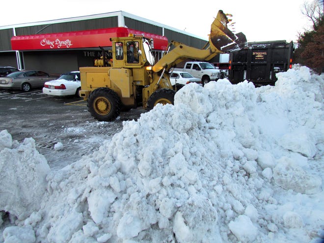 A bucket loader removes snow from the parking lot near Ming Dynasty.