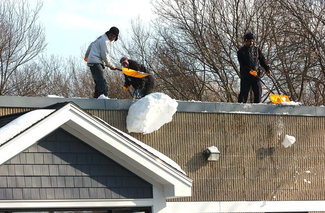 Workers from Nessralla's Landscaping in Avon shovel the snow off the roof of J.M. Pet Resort on Pearl Street in Brockton.