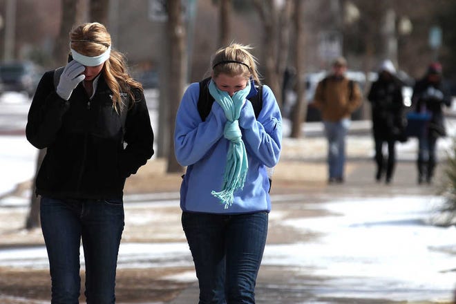 Katie Rustmann, left, and Amy Carey try to keep warm while walking to the Texas Tech campus Tuesday. A bitter arctic front brought frigid temperatures and below-zero wind chills to the South Plains.
