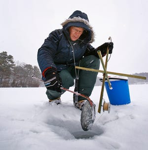 Jim Kasper ladles ice from his fishing hole at Little Pond in Plymouth.