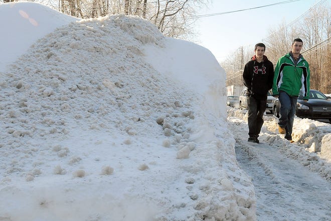 Nick Avila, 16, and Drew Lorenzo, 15, right, passed by huge snowbanks on their way home from Milford High School on Friday.