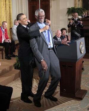 President Barack Obama reaches up to present a 2010 Presidential Medal of Freedom to basketball hall of fame member and former Boston Celtics coach and captain Bill Russell on Tuesday, Feb. 15, 2011, during a ceremony in the East Room of the White House.
