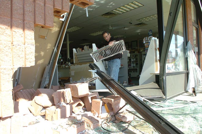 David Bluestein of Sharon, owner of West Side Graphics in North Easton, finds a grill from the front end of a vehicle that crashed through his store on Thursday Feb. 17, 2011.