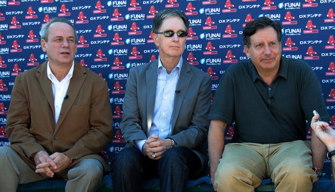 Red Sox president and CEO Larry Lucchino (left), principal owner John Henry and Chairman Tom Werner (right) talk with reporters on the first day of spring training yesterday.