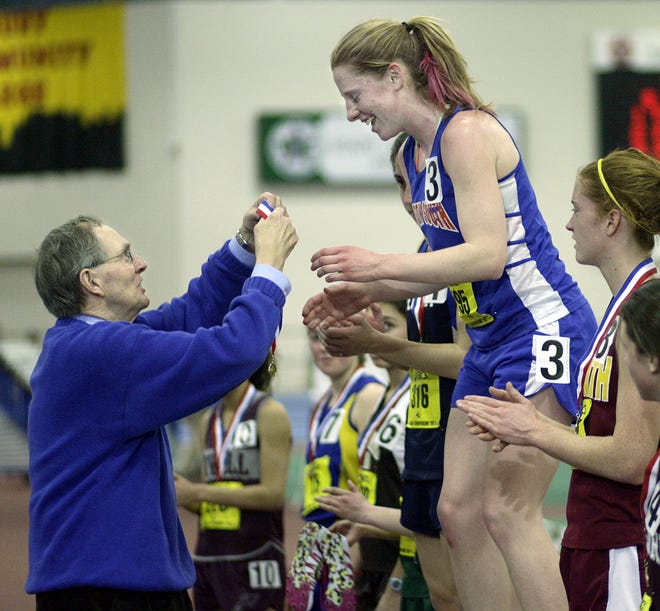 Newton South's Kathy O'Keefe receives a first-place ribbon from MIAA Assistant Director Dick Baker after winning the mile run during Friday night's Division 1 State track meet at the Reggie Lewis Center in Boston.