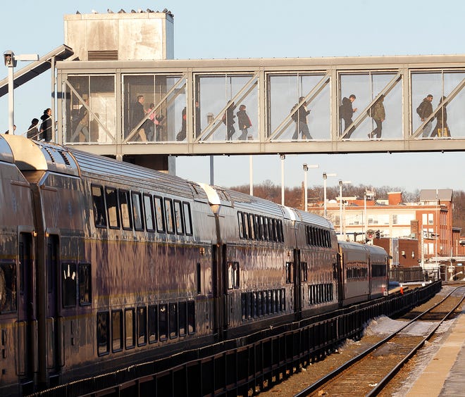 Commuters cross a bridge over the railroad tracks after getting off an outbound train yesterday afternoon in Framingham.