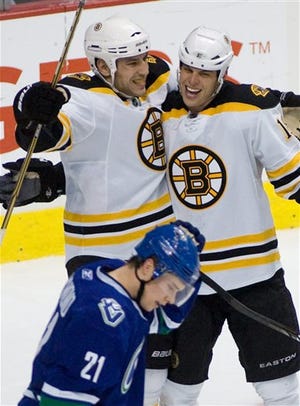Boston Bruins rightwing Nathan Horton (18), right, is congratulated on his second period goal by teammate Milan Lucic (17) while Vancouver Canucks leftwing Mason Raymond (21) skates by during an NHL hockey game in Vancouver, British Columbia, Saturday, Feb. 26, 2011. (AP Photo/The Canadian Press, Geoff Howe)