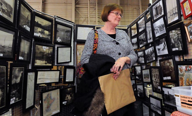 Andrea Daley of Holliston walks through a display of vintage photographs during the Citizen Scholarship Foundation of Holliston's 44th Annual Antique Show yesterday afternoon at Holliston High School.