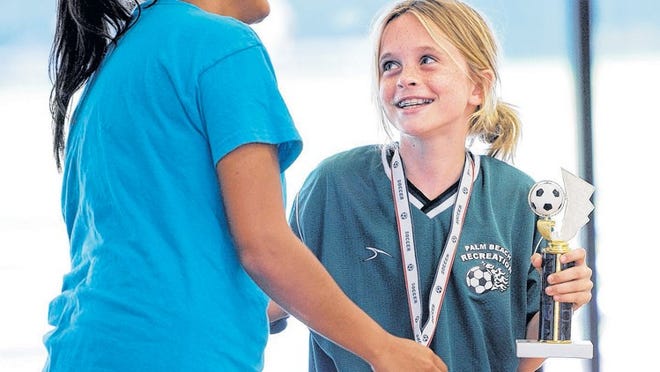 Liz Williams accepts a sportsmanship award from her coach Esabelle Herrera during the youth soccer awards ceremony at the Recreation Center. ‘She has been a trooper,’ Herrera said of Williams. Williams had been unable to play because of a broken foot, but has attended games and practices to support her team, Duffy’s. As the soccer season ends, lacrosse is on its way in.