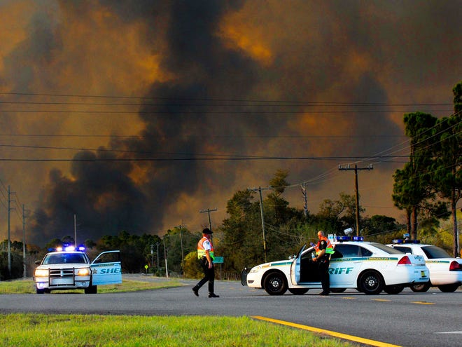 In this Monday, Feb. 28, 2011 photo, Brevard County Sheriff's deputies close down U.S. Highway 1, in Scottsmoor, Fla., due to a 10,000-acre brush fire burning near the Volusia and Brevard County line. The Florida Highway Patrol has reopened a roughly 30-mile stretch of Interstate 95 on the state's central Atlantic coast that was closed because of the fast-moving wildfire. (AP Photo)