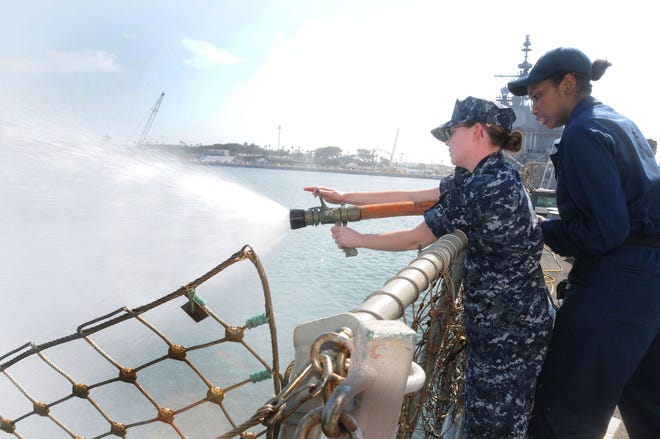 Hospital Corpsman 3rd Class Marjorie Hartman, assigned to Naval Hospital Jacksonville, learns the different positions of the fire hose from Damage Control Fireman Layna Simon, assigned to USS Roosevelt (DDG 80), during Operation Haze Gray. Operation Haze Gray is an exercise aimed at having medical corps reservist and active-duty corpsmen with little or no shipboard experience to become part of a homported crew and conduct "shipboard life" training.