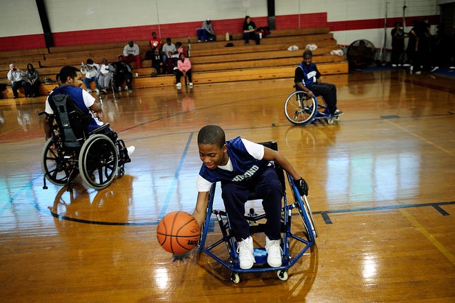 Troy Williams picks up a basketball to warm up before a game against school board members and administrators. Despite never having played basketball before becoming disabled a year ago, Williams scored all of his team's 35 points on the way to Thursday evening's victory.