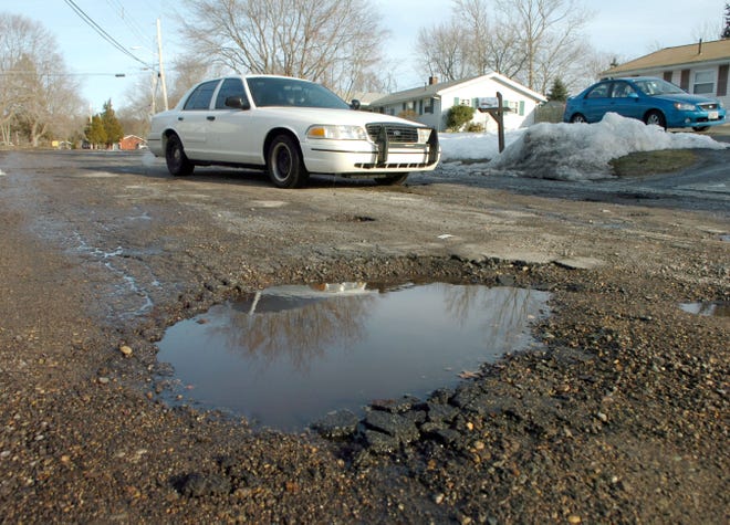 A driver steers onto the wrong side of the road to avoid a pothole on Tina Avenue in Brockton on Friday.