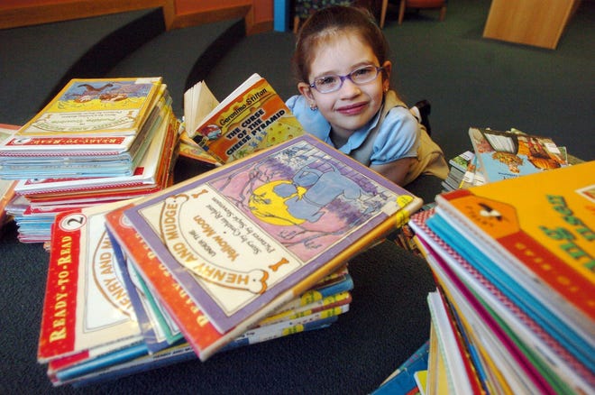 Bella Grace Tyler, 7, of Norwich, a second grade student at Veterans Memorial School, with some of the 700 books she has read since last summer.